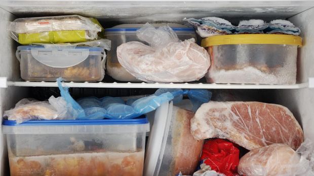 Frozen food inside a freezer. Lots of leftovers in plastic containers.