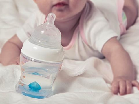Bottle of water for baby. Infant child on blurred background