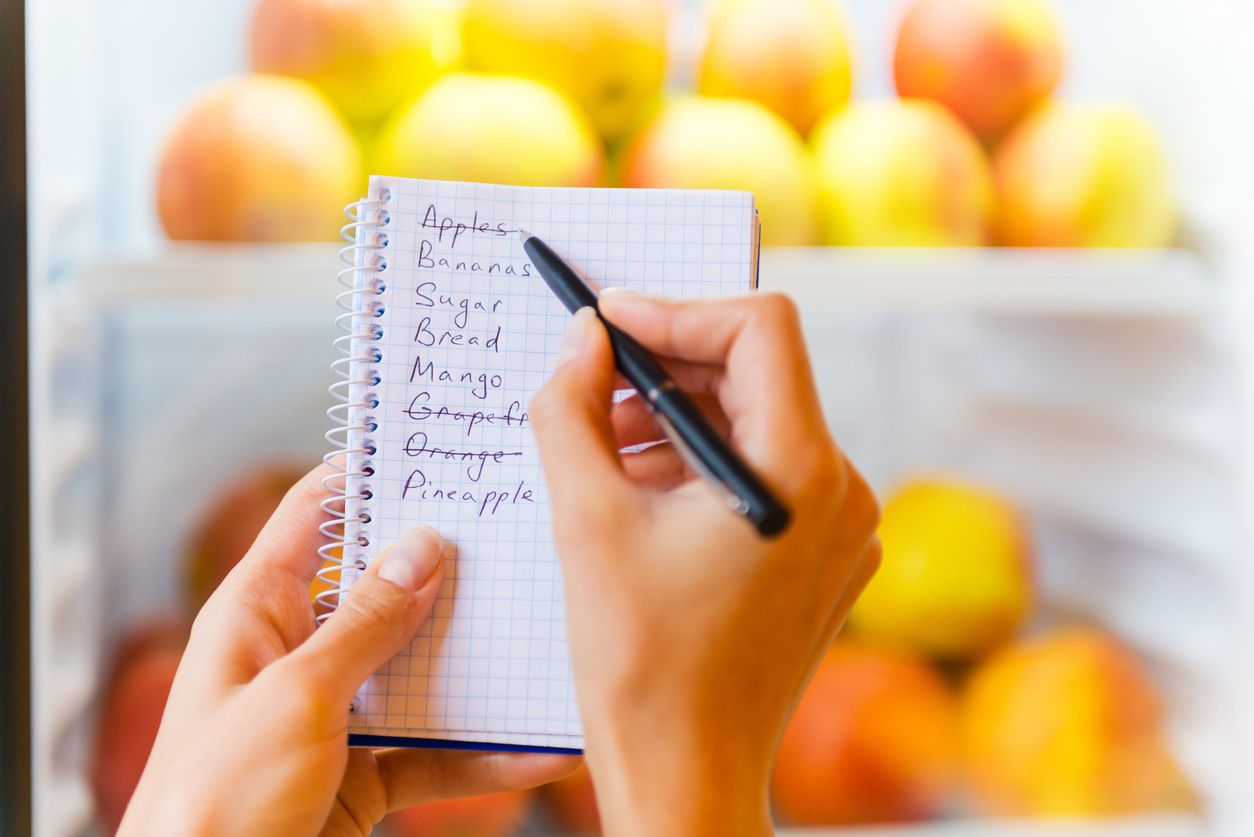 Close-up of woman checking shopping list with apples in the background