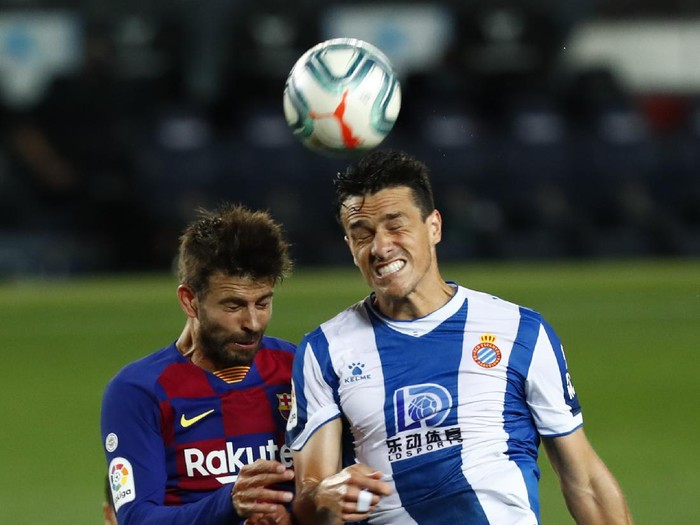 Barcelonas Gerard Pique fights for the ball against Espanyols Bernardo Espinosa during the Spanish La Liga soccer match between FC Barcelona and RCD Espanyol at the Camp Nou stadium in Barcelona, Spain, Wednesday, July 8, 2020. (AP Photo/Joan Monfort)