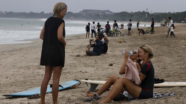 Tourists are seen at Kuta beach, Bali, Indonesia on Thursday, July 9, 2020. Indonesia's resort island of Bali reopened after a three-month virus lockdown Thursday, allowing local people and stranded foreign tourists to resume public activities before foreign arrivals resume in September. (AP Photo/Firdia Lisnawati)
