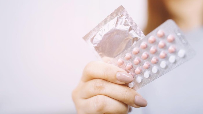 pil kb Close up hand contraceptive pill and condom on with colorful pills strips. Contraception reduces childbirth and pregnant concept.