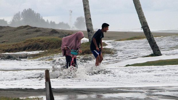 Sejumlah anak melintasi genangan banjir rob di Desa Gampong Belakang, Johan Pahlawan, Aceh Barat, Aceh, Sabtu (11/7/2020). Banjir rob tersebut mengakibatkan ratusan rumah warga terendam. ANTARA FOTO/Syifa Yulinnas/wsj..