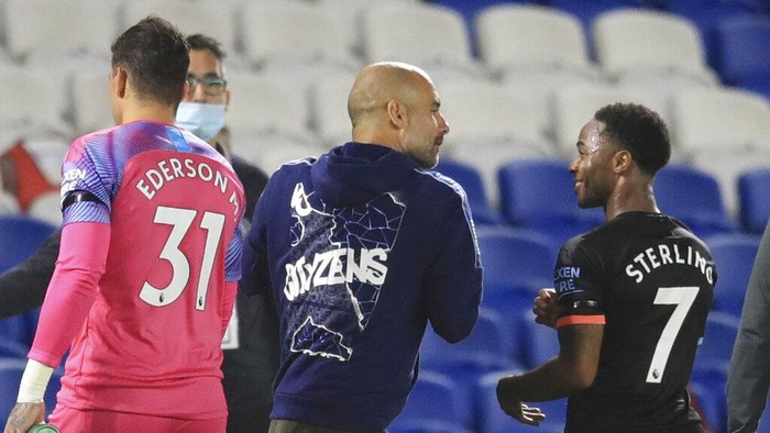 Manchester Citys Raheem Sterling, right, talks to Manchester Citys head coach Pep Guardiola at the end of the English Premier League soccer match between Brighton and Manchester City at the Falmer stadium in Brighton, England, Saturday, July 11, 2020. (Adam Davy/Pool via AP)