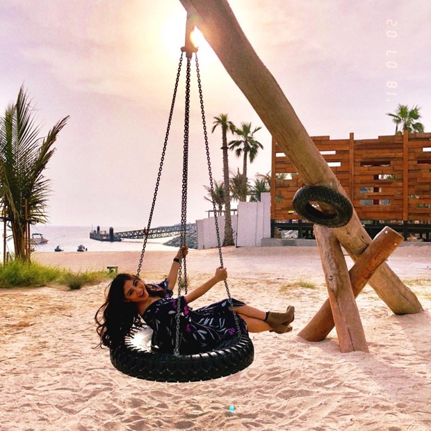 Bersantai di atas ayunan ban bersama hamparan pasir berhasil membuat Margin senyum sumringah