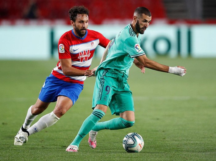 GRANADA, SPAIN - JULY 13:  Karim Benzema of Real Madrid is tackled by Germán Sánchez of Granada during the Liga match between Granada CF and Real Madrid CF at on July 13, 2020 in Granada, Spain. Football Stadiums around Europe remain empty due to the Coronavirus Pandemic as Government social distancing laws prohibit fans inside venues resulting in all fixtures being played behind closed doors. (Photo by Fran Santiago/Getty Images)