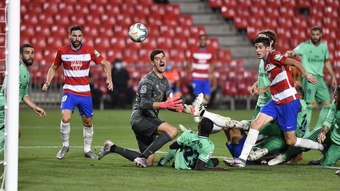 Granadas Spanish forward Carlos Fernandez (R) challenges Real Madrids Belgian goalkeeper Thibaut Courtois (L) and French defender Ferland Mendy (down) during the Spanish league football match Granada FC vs Real Madrid CF at Nuevo Los Carmenes stadium in Granada on July 13, 2020. (Photo by JORGE GUERRERO / AFP)