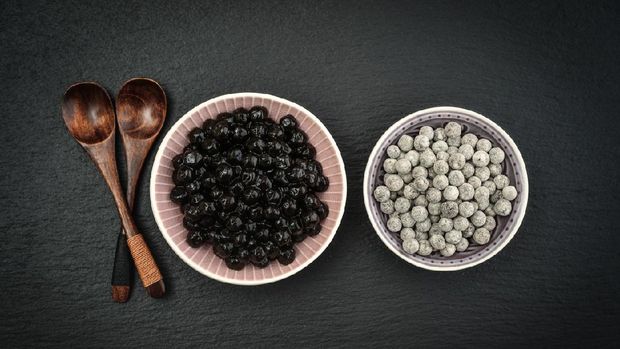 Boiled and Raw Tapioca Pearls in plates on black slate background. For Bubble tea concepts.