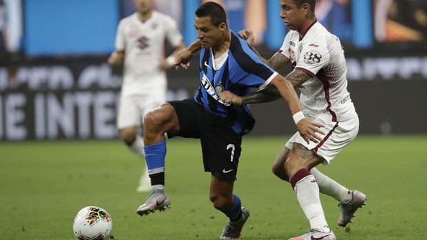 Inter Milan's Alexis Sanchez, left, fights for the ball with Torino's Armando Izzo during a Serie A soccer match between Inter Milan and Torino, at the San Siro stadium in Milan, Italy, Monday, July 13, 2020. (AP Photo/Luca Bruno
