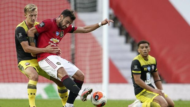 Manchester United's Bruno Fernandes kicks the ball as Southampton's James Ward-Prowse, left, watches during the English Premier League soccer match between Manchester United and Southampton at Old Trafford in Manchester, England, Monday, July 13, 2020. (AP Photo/Dave Thompson,Pool)