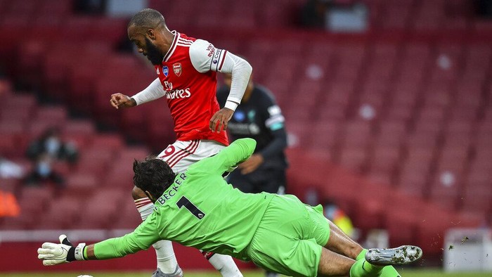Arsenals Alexandre Lacazette runs past Liverpools goalkeeper Alisson before scoring his team first goal during the English Premier League soccer match between Arsenal and Liverpool at the Emirates Stadium in London, England, Wednesday, July 15, 2020. (Glyn Kirk/Pool via AP)