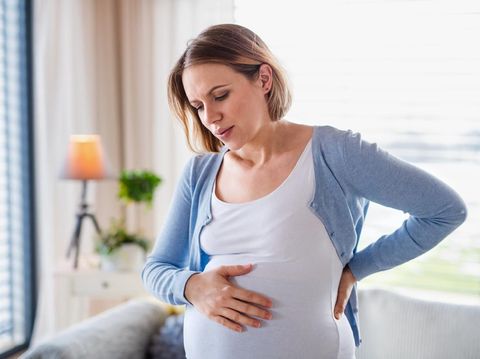 A portrait of pregnant young woman indoors at home, feeling tired.