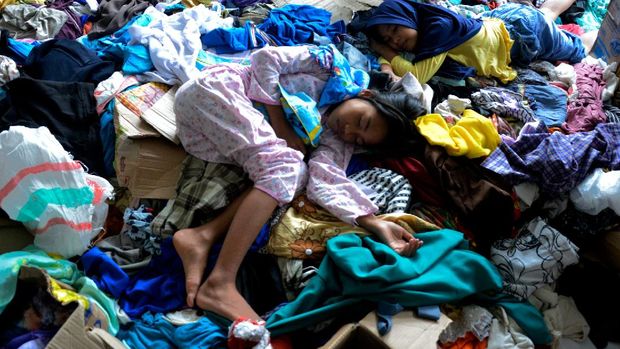 Anak-anak korban banjir bandang berada di tumpukan  pakaian layak pakai saat mengungsi di kawasan kantor Bupati Luwu Utara, Sulawesi Selatan, Kamis (16/7/2020).  Sebanyak 15.994 jiwa  mengungsi di sejumlah posko pengungsian karena rumah mereka rusak dan hilang akibat tertimbun lumpur setelah diterjang banjir bandang. ANTARA FOTO/Abriawan Abhe/nz