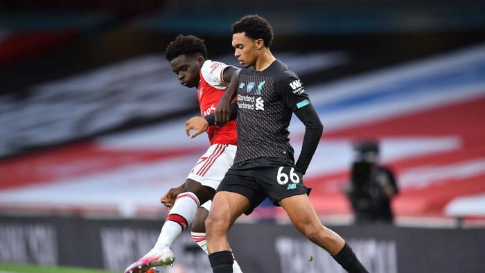LONDON, ENGLAND - JULY 15: Bukayo Saka of Arsenal  battles for possession with  Trent Alexander-Arnold of Liverpool  during the Premier League match between Arsenal FC and Liverpool FC at Emirates Stadium on July 15, 2020 in London, England. Football Stadiums around Europe remain empty due to the Coronavirus Pandemic as Government social distancing laws prohibit fans inside venues resulting in all fixtures being played behind closed doors. (Photo by Glyn Kirk/Pool via Getty Images)