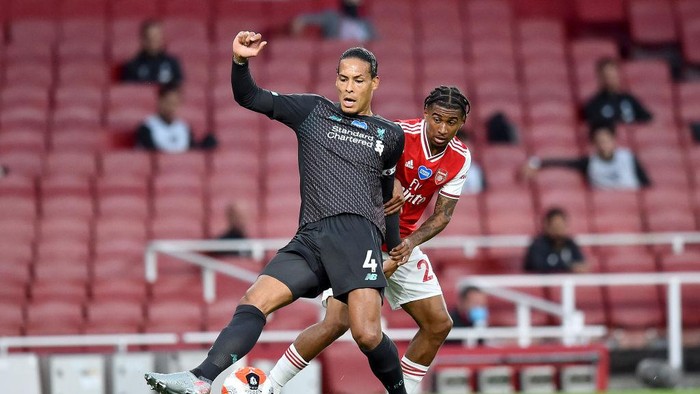 LONDON, ENGLAND - JULY 15: Virgil van Dijk of Liverpool is challenged by Reiss Nelson of Arsenal during the Premier League match between Arsenal FC and Liverpool FC at Emirates Stadium on July 15, 2020 in London, England. Football Stadiums around Europe remain empty due to the Coronavirus Pandemic as Government social distancing laws prohibit fans inside venues resulting in all fixtures being played behind closed doors. (Photo by Glyn Kirk/Pool via Getty Images)