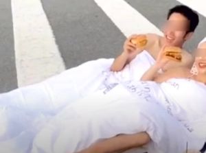 Foto Tiduran di Tengah Jalan Sambil Makan Burger, Pasangan Ini Dikecam Netizen