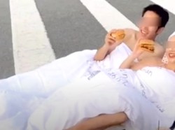 Foto Tiduran di Tengah Jalan Sambil Makan Burger, Pasangan Ini Dikecam Netizen