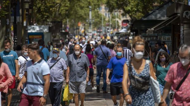 People walk along the Ramblas of Barcelona, Spain, Thursday, July 16, 2020. With Europe's summer vacation season kicking into high gear for millions weary of months of lockdown, scenes of drunken British and German tourists on Spain's Mallorca island ignoring social distancing rules and reports of American visitors flouting quarantine measures in Ireland are raising fears of a resurgence of infections in countries that have battled for months to flatten the COVID-19 curve. (AP Photo/Emilio Morenatti)
