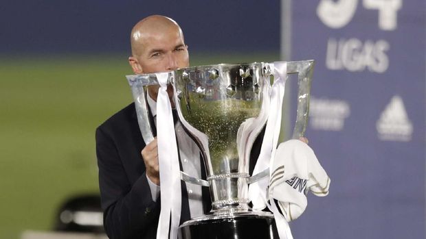 Real Madrid's head coach Zinedine Zidane, holds the trophy as he poses for the photographers after winning the Spanish La Liga 2019-2020 following a soccer match between Real Madrid and Villareal at the Alfredo di Stefano stadium in Madrid, Spain, Thursday, July 16, 2020. (AP Photo/Bernat Armangue)