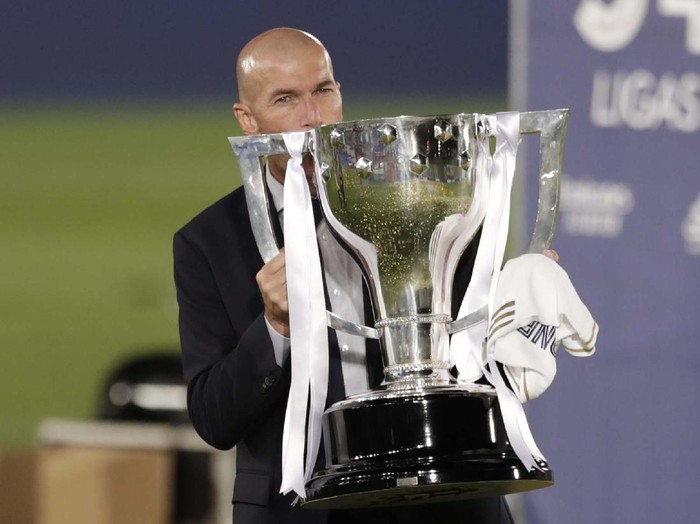 Real Madrid's head coach Zinedine Zidane, holds the trophy as he poses for the photographers after winning the Spanish La Liga 2019-2020 following a soccer match between Real Madrid and Villareal at the Alfredo di Stefano stadium in Madrid, Spain, Thursday, July 16, 2020. (AP Photo/Bernat Armangue)