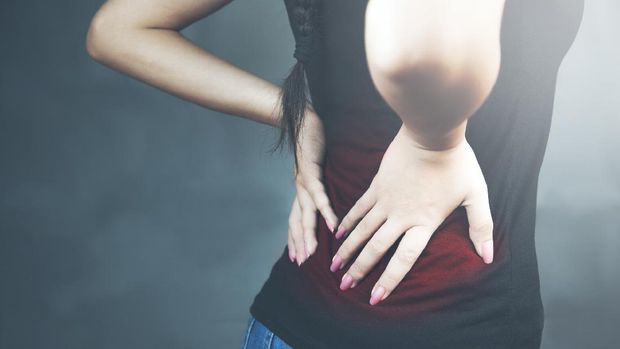 young woman with backache lower back pain colored in red isolated on dark background