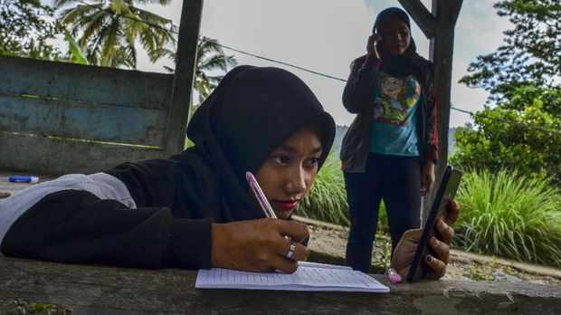 Siswa kelas IX Sekolah Menengah Pertama (SMP) Plus Pasawahan mengerjakan tugas sekolah di pos kamling Desa Pasawahan, Kabupaten Ciamis, Jawa Barat, Kamis, (16/7/2020). Pelajar yang tinggal di desa terpecil terpaksa mengerjakan tugas sekolah di luar rumah lantaran keterbatasan jaringan internet sedangkan sekolah hanya bisa memfasilitasi kegiatan belajar mengajar (KBM) secara daring mengunakan aplikasi WhatsApp Grup serta Facebook Messenger. ANTARA FOTO/Adeng Bustomi/agr/aww.