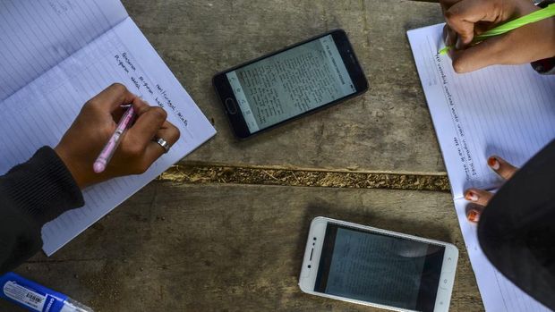 Siswa kelas IX Sekolah Menengah Pertama (SMP) Plus Pasawahan mengerjakan tugas sekolah di pos kamling Desa Pasawahan, Kabupaten Ciamis, Jawa Barat, Kamis, (16/7/2020). Pelajar yang tinggal di desa terpecil terpaksa mengerjakan tugas sekolah di luar rumah lantaran keterbatasan jaringan internet sedangkan sekolah hanya bisa memfasilitasi kegiatan belajar mengajar (KBM) secara daring mengunakan aplikasi WhatsApp Grup serta Facebook Messenger. ANTARA FOTO/Adeng Bustomi/agr/aww.