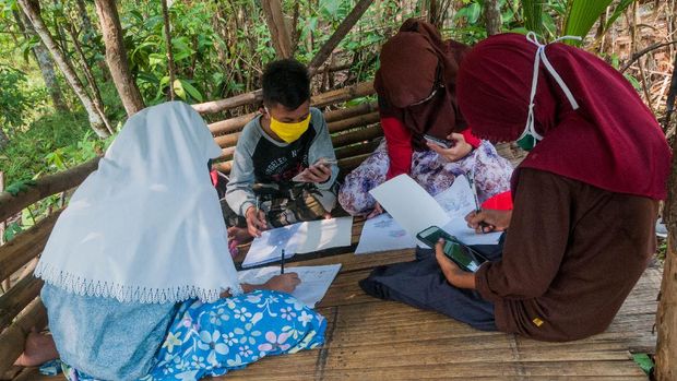 Sejumlah siswa SDN 1 Inten Jaya mengerjakan tugas melalui gawainya di Kampung Lebak Limus, Lebak, Banten, Senin (20/7/2020). Sejumlah siswa yang tinggal di daerah pelosok tersebut kesulitan dalam mengikuti kegiatan belajar mengajar (KBM) secara daring dan tepaksa menempuh perjalanan hingga satu kilometer dari kediamannya menuju ke dataran yang lebih tinggi agar mendapatkan jaringan internet guna mengerjakan tugas sekolah melalui gawai yang nantinya dikirim melalui aplikasi percakapan WhatssApp. ANTARA FOTO/Muhammad Bagus Khoirunas/agr/wsj.