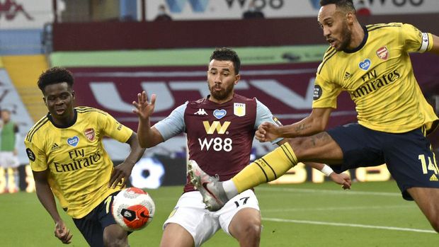 Arsenal's Pierre-Emerick Aubameyang, right, kicks at the ball as Aston Villa's Trezeguet, centre, and Arsenal's Bukayo Saka, left, watch during the English Premier League soccer match between Aston Villa and Arsenal at Villa Park in Birmingham, England, Tuesday, July 21, 2020. (AP Photo/Rui Vieira,Pool)