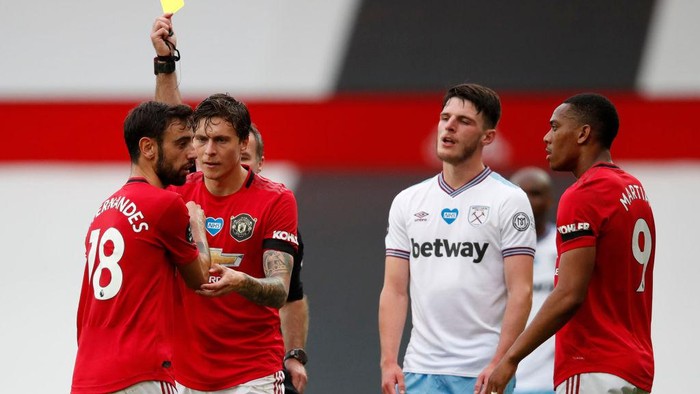 MANCHESTER, ENGLAND - JULY 22: Bruno Fernandes of Manchester United is shown a yellow card by Match Referee, Paul Tierney during the Premier League match between Manchester United and West Ham United at Old Trafford on July 22, 2020 in Manchester, England. Football Stadiums around Europe remain empty due to the Coronavirus Pandemic as Government social distancing laws prohibit fans inside venues resulting in all fixtures being played behind closed doors. (Photo by Clive Brunskill/Getty Images)