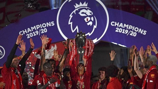 Liverpool's Roberto Firmino holds the English Premier League trophy aloft after it was presented following the Premier League soccer match between Liverpool and Chelsea at Anfield stadium in Liverpool, England, Wednesday, July 22, 2020. (Paul Ellis, Pool via AP)