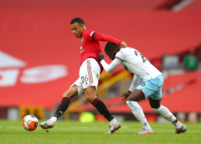 MANCHESTER, ENGLAND - JULY 22: Mason Greenwood of Manchester United and Arthur Masuaku of West Ham United battle for the ball during the Premier League match between Manchester United and West Ham United at Old Trafford on July 22, 2020 in Manchester, England. Football Stadiums around Europe remain empty due to the Coronavirus Pandemic as Government social distancing laws prohibit fans inside venues resulting in all fixtures being played behind closed doors. (Photo by Catherine Ivill/Getty Images)