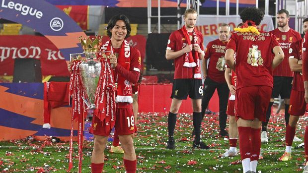 Liverpool's Takumi Minamino holds the English Premier League trophy aloft after it was presented following the Premier League soccer match between Liverpool and Chelsea at Anfield stadium in Liverpool, England, Wednesday, July 22, 2020. (Paul Ellis, Pool via AP)