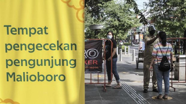 Petugas Jogoboro memeriksa suhu tubuh pengunjung di Jalan Malioboro, DI Yogyakarta. ANTARA FOTO/Hendra Nurdiyansyah