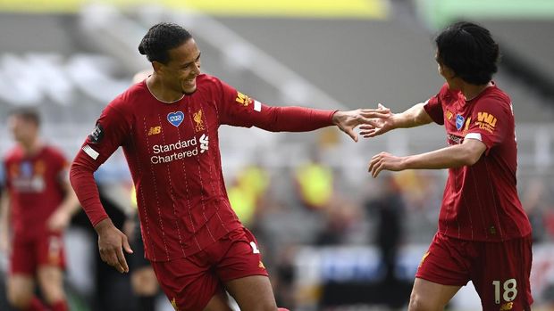 Liverpool's Virgil van Dijk, left, celebrates with Takumi Minamino after his side's first goal during the English Premier League soccer match between Newcastle and Liverpool at St. James' Park in Newcastle, England, Sunday, July 26, 2020. (Laurence Griffiths, Pool via AP)