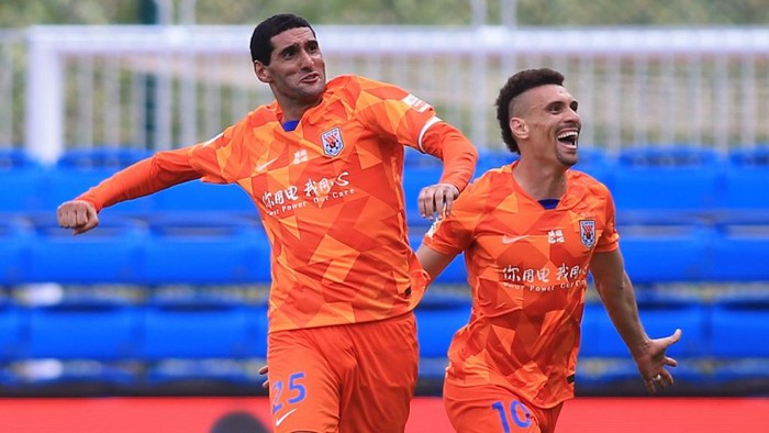 Marouane Fellaini (L) of Shandong Luneng celebrates with teammate Moises after Fellaini scored against Dalian Pro during their Chinese Super League (CSL) football match in Dalian in Chinas northeastern Liaoning province on July 26, 2020. - Fellaini, who spent three weeks in hospital with the COVID-19 coronavirus, scored a hat-trick of headers in less than 10 minutes to give Shandong Luneng a 3-2 victory over Rafa Benitezs Dalian Pro. (Photo by STR / AFP) / China OUT
