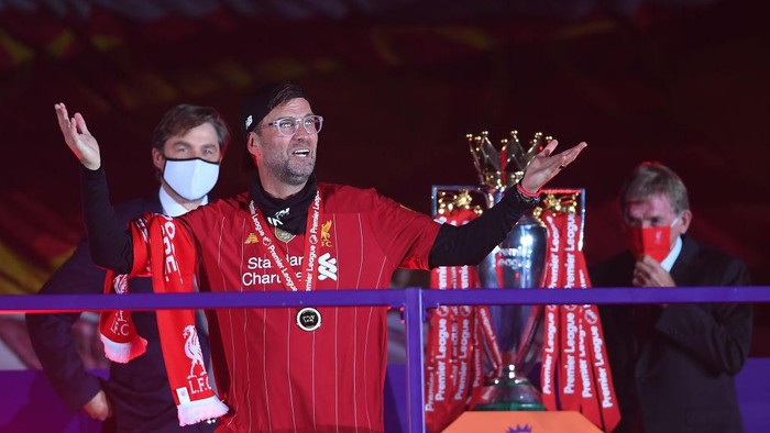 LIVERPOOL, ENGLAND - JULY 22: Jurgen Klopp, Manger of Liverpool puts on his winners medal after being presented by Richard Masters, Chief Executive of the Premier League and Liverpool legend Sir Kenny Dalglish during the Presentation ceremony of  the Premier League match between Liverpool FC and Chelsea FC at Anfield on July 22, 2020 in Liverpool, England. Football Stadiums around Europe remain empty due to the Coronavirus Pandemic as Government social distancing laws prohibit fans inside venues resulting in games being played behind closed doors. (Photo by Laurence Griffiths/Getty Images)