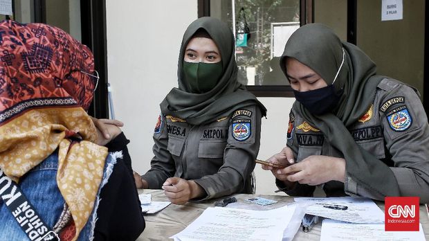 Petugas memberikan denda kepada warga yang tidak mengenakan masker di kawasan Jalan Sukmajaya, Depok, Jawa Barat, Senin (28/7/2020). Warga yang tidak mengenakan masker dikenai denda Rp 50 ribu.CNN Indonesia/Andry Novelino