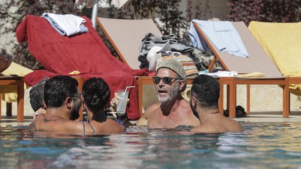 Lebanese people gather at a swimming pool in the upmarket Faqra Club in the Lebanese mountains north of Beirut on July 25, 2020. - Panama hats and designer sunglasses, champagne buckets and luxury cars: in the mountain resort town of Faqra, Lebanon's economic crisis is not immediately obvious. Digging into a crunchy salad at an exclusive country club in the Lebanese mountains, Zeina el-Khalil said she was glad to have escaped here for the summer. (Photo by JOSEPH EID / AFP)