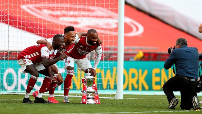 LONDON, ENGLAND - AUGUST 01: Nicolas Pepe of Arsenal , Pierre-Emerick Aubameyang of Arsenal  and Alexandre Lacazette of Arsenal pose for photographs with the FA Cup Trophy after their teams victory during the Heads Up FA Cup Final match between Arsenal and Chelsea at Wembley Stadium on August 01, 2020 in London, England. Football Stadiums around Europe remain empty due to the Coronavirus Pandemic as Government social distancing laws prohibit fans inside venues resulting in all fixtures being played behind closed doors. (Photo by Catherine Ivill/Getty Images)
