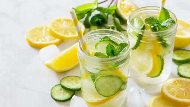 Refreshing summer drink with lemon and cucumber on a background of stone. The concept of eating vegetarians, fresh vitamins, a homemade refreshing fruit drink.