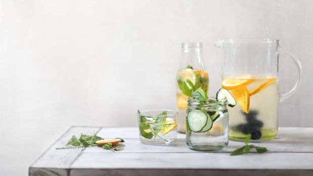 Refreshing summer drink with lemon and cucumber on a background of stone. The concept of eating vegetarians, fresh vitamins, a homemade refreshing fruit drink.