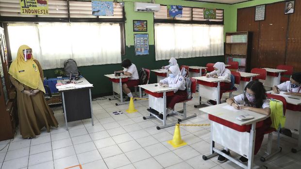 Indonesian students and their teacher wear face masks as a precaution against the new coronavirus as they study at a class in Bekasi on the outskirts of Jakarta, Indonesia, Monday, Aug. 3, 2020. (AP Photo/Achmad Ibrahim)