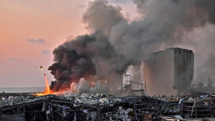 EDITORS NOTE: Graphic content / A helicopter puts out a fire at the scene of an explosion at the port of Lebanons capital Beirut on August 4, 2020. (Photo by STR / AFP)