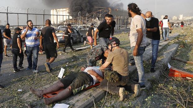 Ledakan di Beirut, Libanon Rescue workers help an injured man at the explosion scene that hit the seaport of Beirut, Lebanon, Tuesday, Aug. 4, 2020. (AP Photo/Hussein Malla)