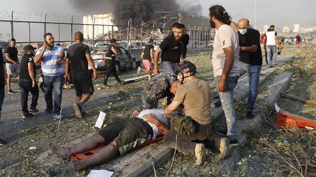 Rescue workers help an injured man at the explosion scene that hit the seaport of Beirut, Lebanon, Tuesday, Aug. 4, 2020. (AP Photo/Hussein Malla)