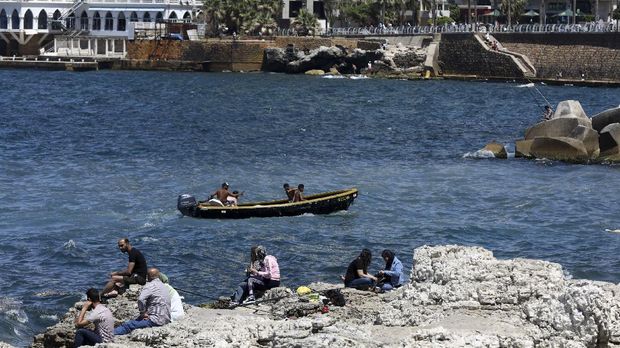 Residents of the Lebanese capital Beirut gather on the rocks along the seaside corniche, despite the lingering threat of the novel coronavirus, on May 31, 2020. (Photo by ANWAR AMRO / AFP)