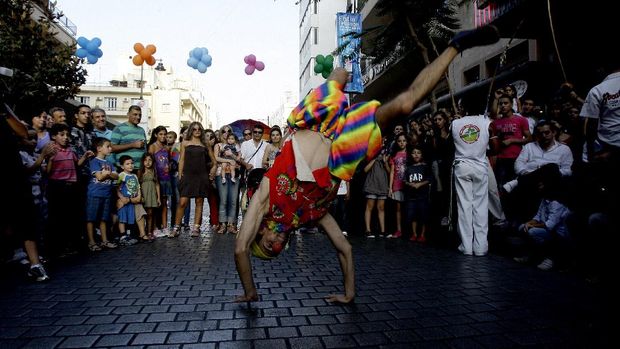 People watch an acrobat dressed as a clown perform in Beirut's Hamra thoroughfare on September 10, 2010, the first day of the Maraya entertainment festival which turned the Lebanese capital's most famous shopping district into a pedestrian street for parading vehicles and various performers, including acrobats and mime actors. AFP PHOTO/ANWAR AMRO (Photo by ANWAR AMRO / AFP)