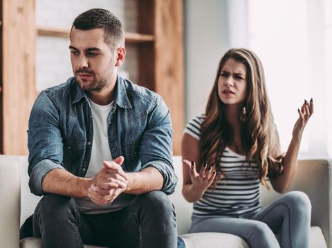 Upset couple at home. Handsome man and beautiful young woman are having quarrel. Sitting on sofa together. Family problems.