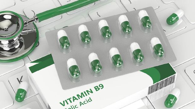 3d render of B9 folic acid pill  lying on keyboard in office